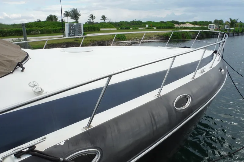 Slide: The Image of 1999 Cruisers 4270 Express yacht docked by lush greenery and calm waters. - 4