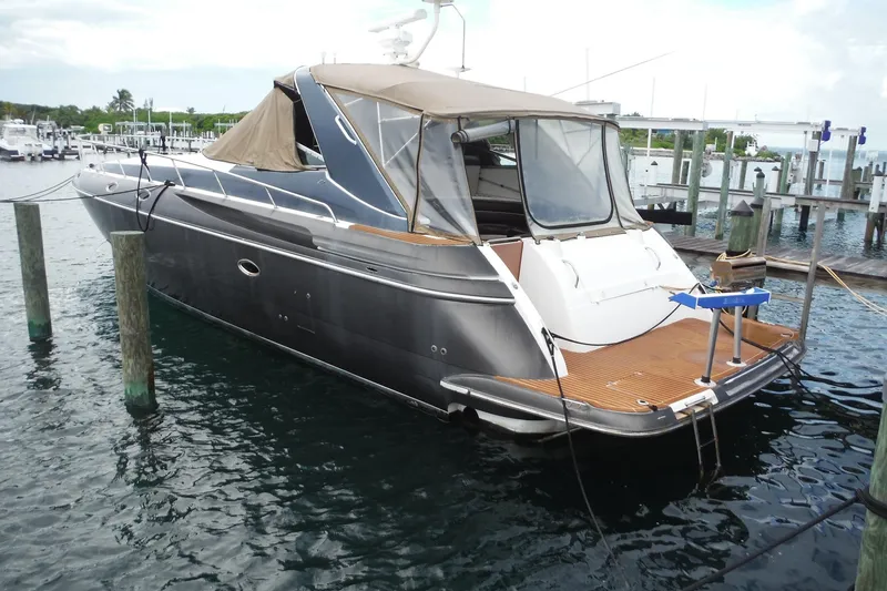 The Image of 1999 Cruisers 4270 Express yacht docked at marina, featuring sleek design and spacious deck. - 1