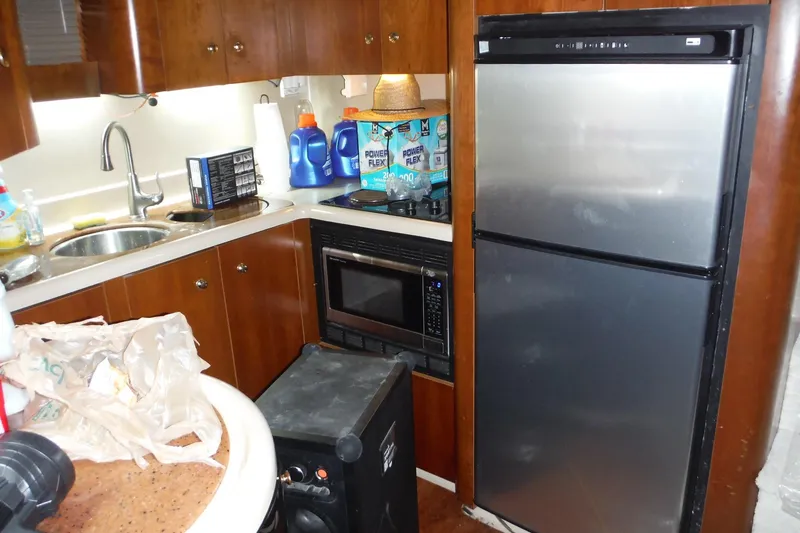 Slide: The Image of 1999 Cruisers 4270 Express yacht kitchen with fridge, microwave, and sink. - 14
