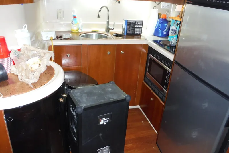 Slide: The Image of 1999 Cruisers 4270 Express yacht kitchen with appliances and wooden cabinetry. - 23