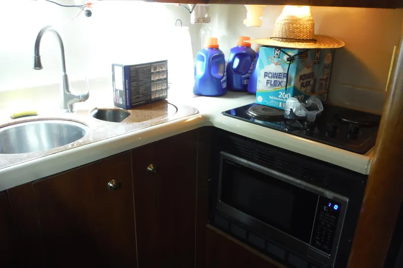 Slide: The Image of 1999 Cruisers 4270 Express kitchen with sink, stove, microwave, and cleaning supplies. - 24