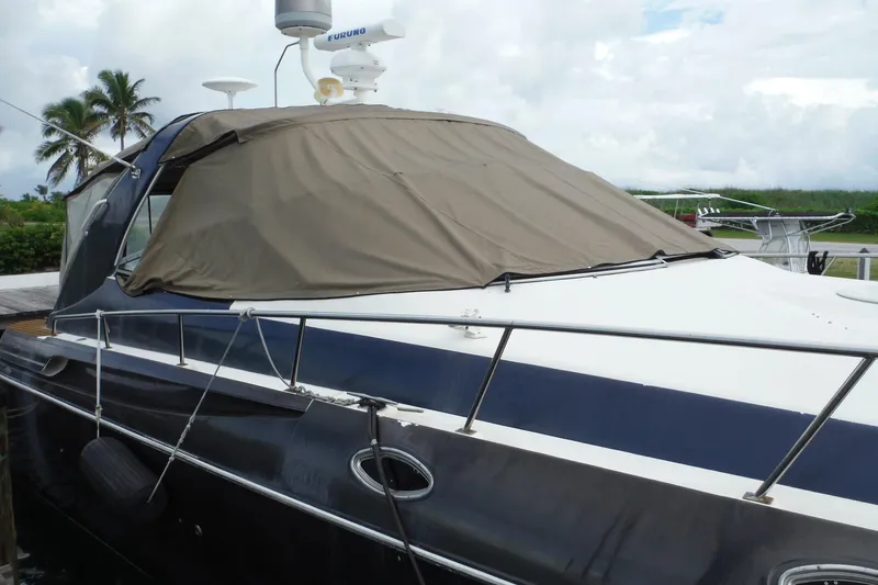 Slide: The Image of 1999 Cruisers 4270 Express yacht docked with cover, palm trees in background. - 3