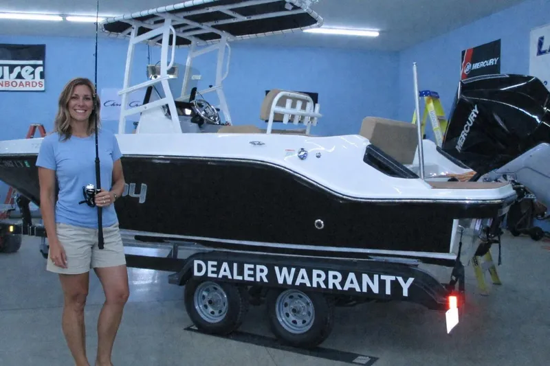 The Image of Woman holding fishing rod beside 2022 Trophy boat with dealer warranty in showroom. - 0