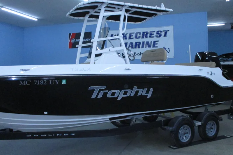 Slide: The Image of 2022 Trophy T22CX boat in showroom, black and white design, on trailer. - 2