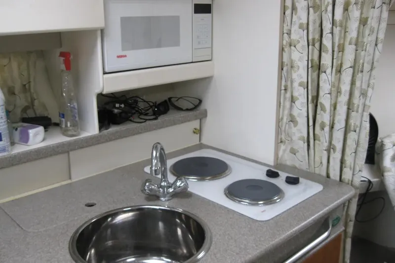 Slide: The Image of Compact kitchen area in a 2000 Formula 31 Performance Cruiser with stove, sink, and microwave. - 28