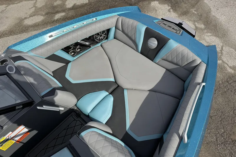 Slide: The Image of 2018 Tigé RZX3 boat interior with gray and blue seating, cup holders, and speakers. - 11