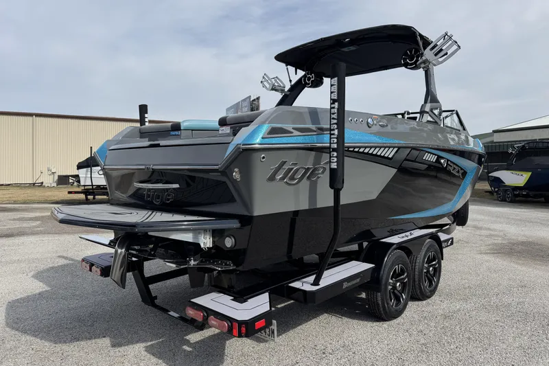 Slide: The Image of 2018 Tigé RZX3 boat on trailer, sleek design with blue accents, parked outdoors. - 3