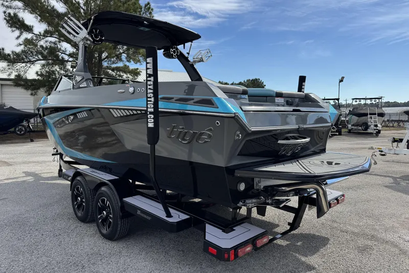 Slide: The Image of 2018 Tigé RZX3 boat on trailer, sleek design, gray and blue accents, parked outdoors. - 6