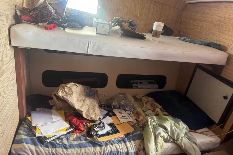 Slide: The Image of Interior of a 1977 Pacifica 44 Convertible boat with cluttered bedding and storage. - 13