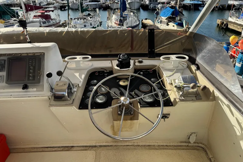 Slide: The Image of 1977 Pacifica 44 Convertible boat helm with steering wheel and control panel at marina. - 20