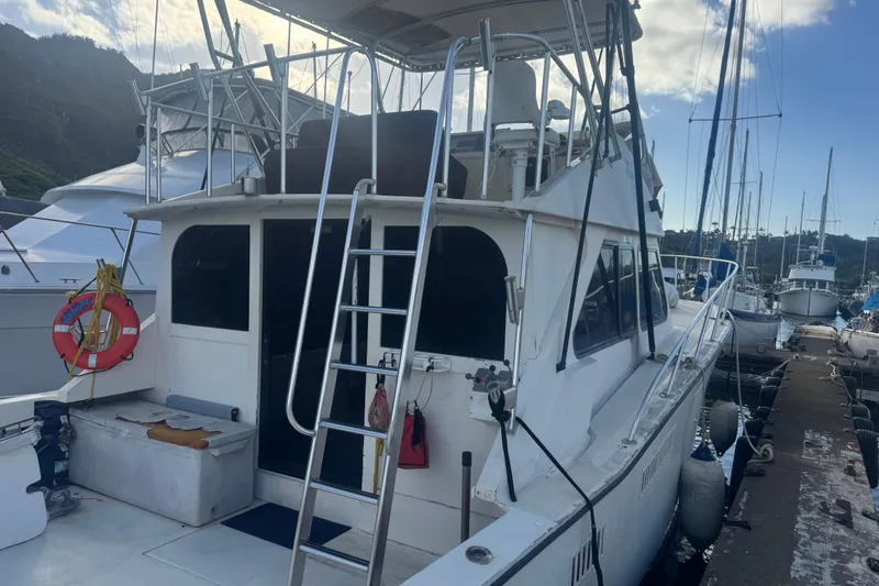 Slide: The Image of 1977 Pacifica 44 Convertible yacht docked at marina, featuring ladder and life preserver. - 5