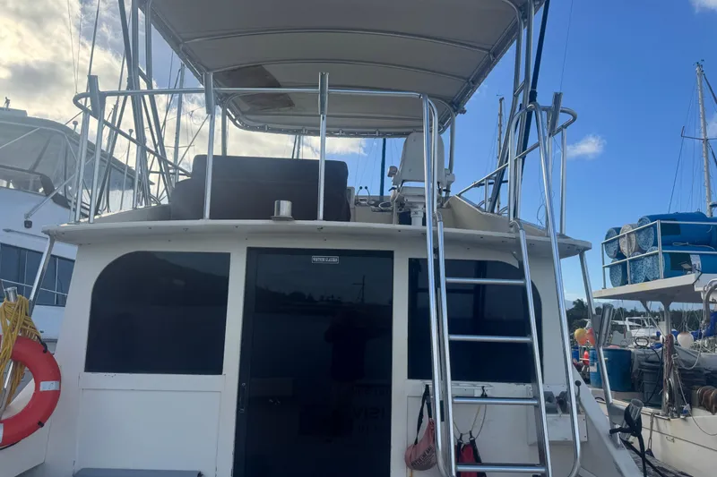 Slide: The Image of 1977 Pacifica 44 Convertible boat with ladder and upper deck, docked at marina. - 7