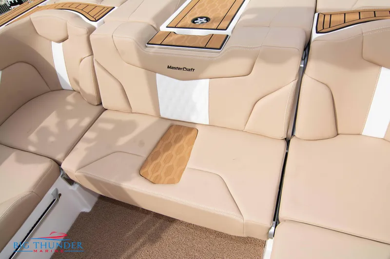 Slide: The Image of 2024 MasterCraft NXT24 boat interior with beige seating and wood accents. - 20