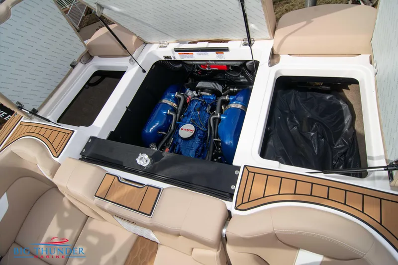 Slide: The Image of 2024 MasterCraft NXT24 boat engine compartment with Ilmor engine, open storage areas, and beige seating. - 48