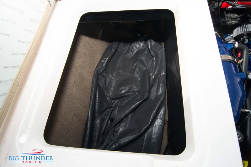 Slide: The Image of Storage compartment in 2024 MasterCraft NXT24 boat, featuring a black cover. - 53