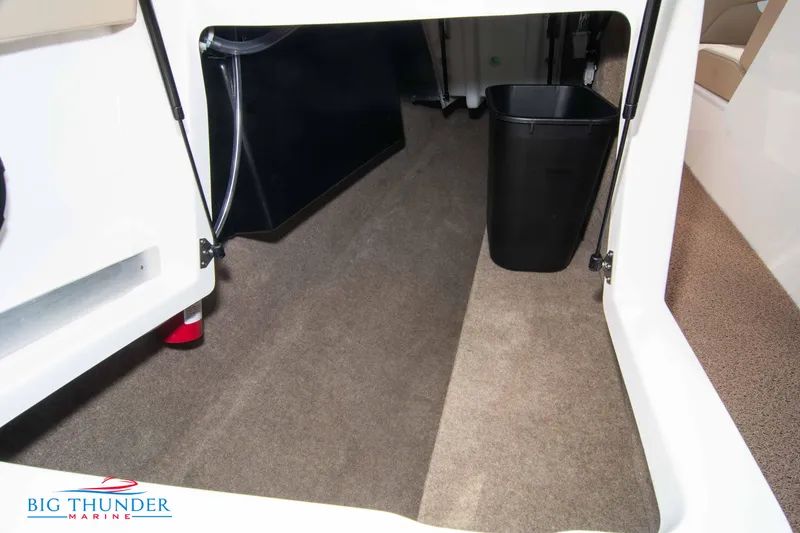 Slide: The Image of 2024 MasterCraft NXT24 boat interior storage compartment with carpet and black trash bin. - 55
