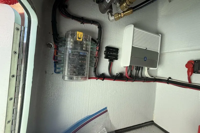 Slide: The Image of Electrical components inside a 2023 Hell's Bay Marquesa boat, featuring wiring and audio equipment. - 11