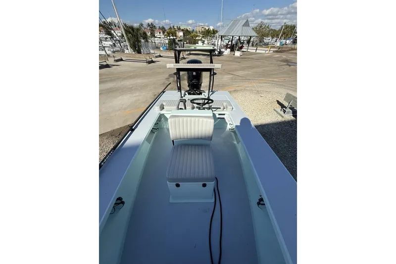 Slide: The Image of 2023 Hell's Bay Marquesa boat interior with seating and steering wheel, docked at marina. - 7