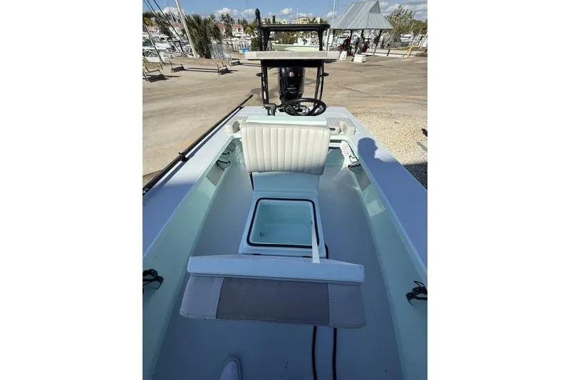 Slide: The Image of 2023 Hell's Bay Marquesa boat interior with seating and steering wheel, docked at marina. - 8