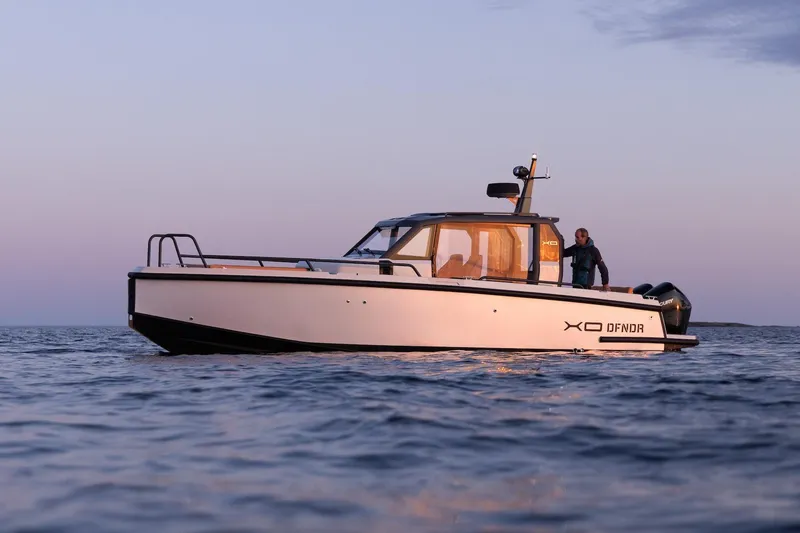 The Image of 2021 XO Boats DFNDR 9 on calm water, surrounded by lush greenery. - 0