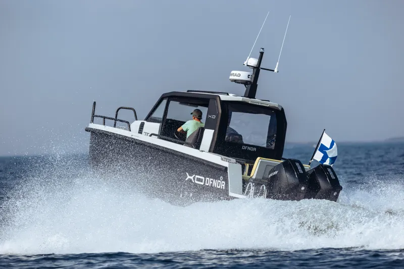 Slide: The Image of 2021 XO Boats DFNDR 9 side view in a garage, showcasing sleek design and logo. - 41