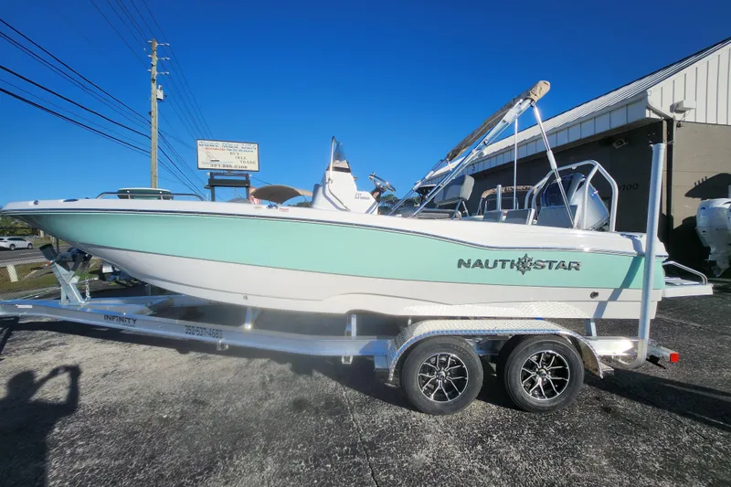 The Image of 2026 NauticStar 211 Hybrid boat on trailer, displayed outdoors under clear blue sky. - 0