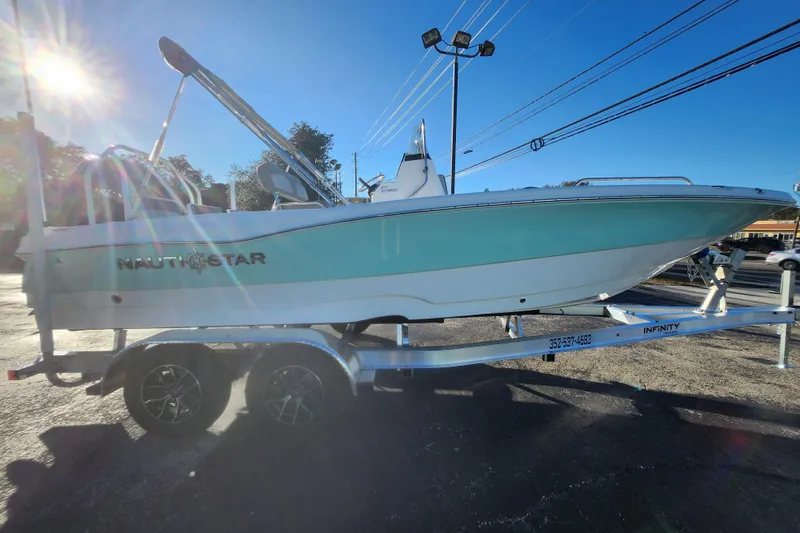 Slide: The Image of 2026 NauticStar 211 Hybrid boat on trailer under bright sunlight. - 10