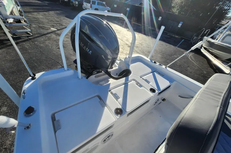 Slide: The Image of 2026 NauticStar 211 Hybrid boat with Yamaha engine, rear deck view in sunlight. - 2
