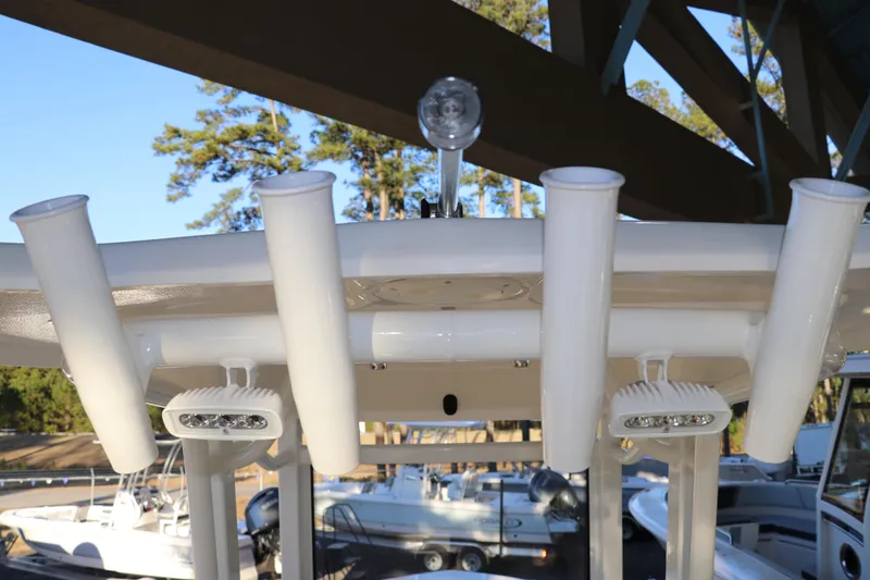 Slide: The Image of 2026 Robalo 246 Cayman boat with rod holders and LED lights, docked under a canopy. - 14