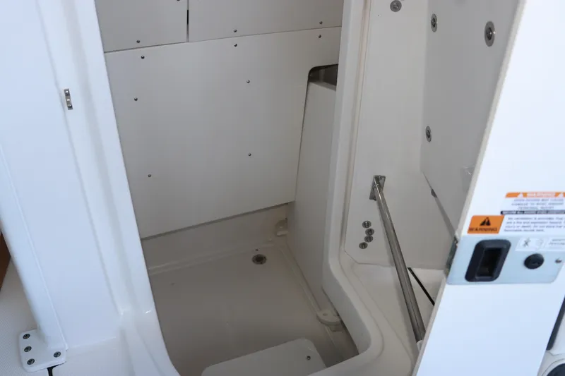 Slide: The Image of 2026 Robalo 246 Cayman interior compartment with white finish and metal fixtures. - 23