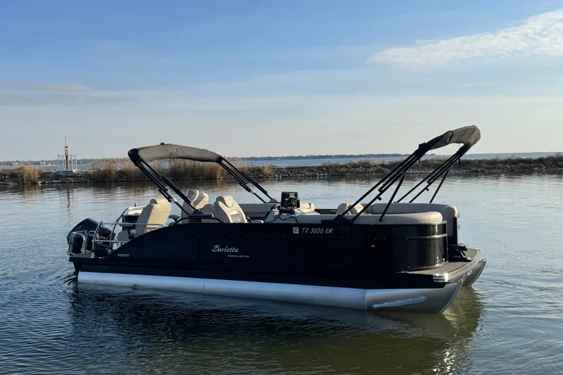 Slide: The Image of 2021 Barletta C22CC pontoon boat on calm water with clear sky background. - 2