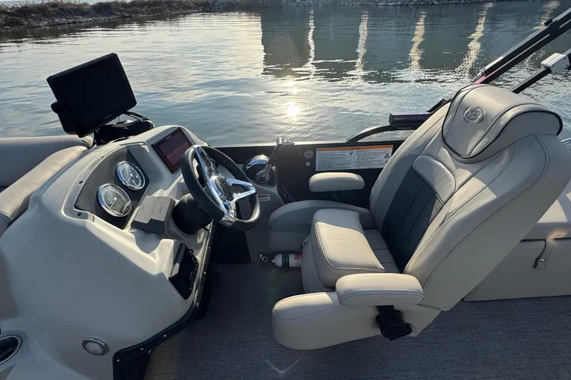 Slide: The Image of 2021 Barletta C22CC boat interior with steering wheel and captain's chair by the water. - 22