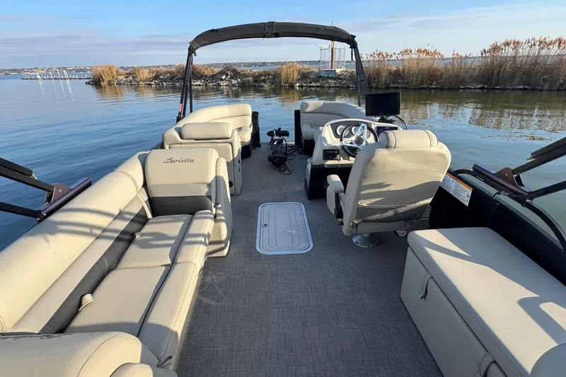 Slide: The Image of 2021 Barletta C22CC pontoon boat interior with plush seating on calm water. - 35