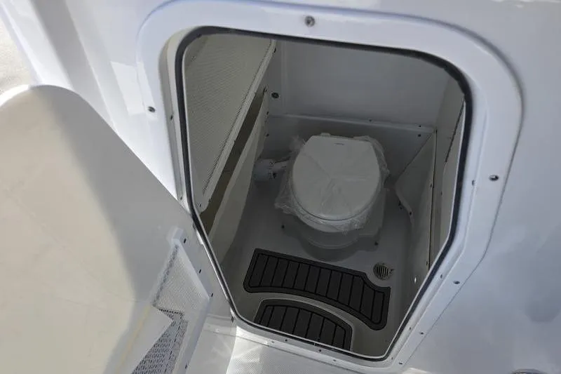 Slide: The Image of Interior of 2026 Sea Hunt Ultra 275 Coffin Box boat, featuring a compact marine toilet. - 9