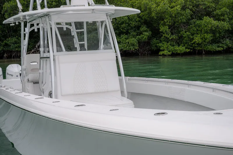 Slide: The Image of 2023 Contender 39 ST boat with sleek design, docked near lush greenery. - 10