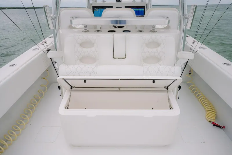 Slide: The Image of 2023 Contender 39 ST boat interior with open storage compartment, white seating, and fishing rod holders. - 33