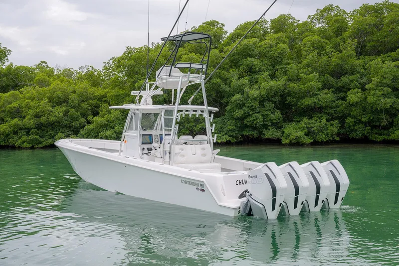 Slide: The Image of 2023 Contender 39 ST boat with quad engines on calm water, surrounded by lush greenery. - 4