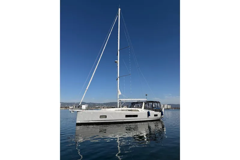The Image of 2022 Beneteau Oceanis 461 sailboat on calm water under clear blue sky. - 0