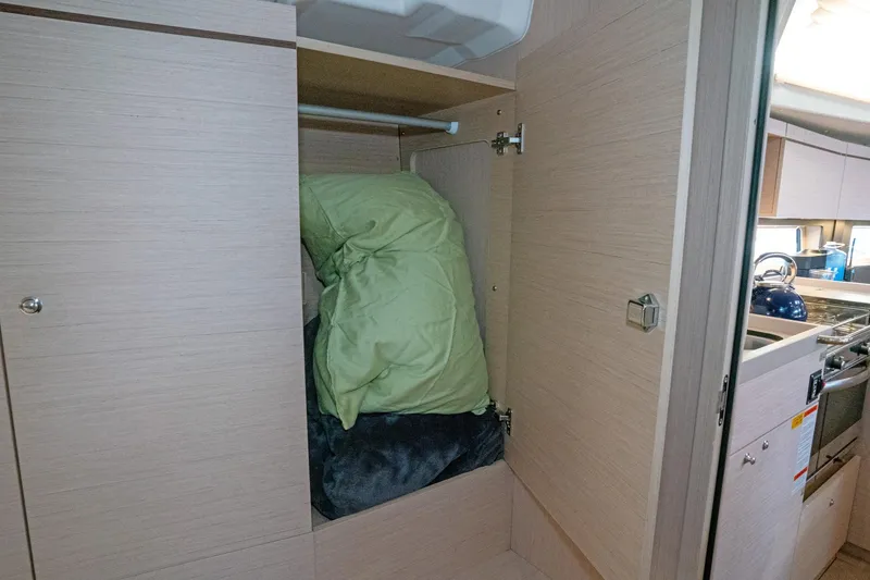 Slide: The Image of Interior storage space on 2022 Beneteau Oceanis 461 sailboat with green bedding. - 11