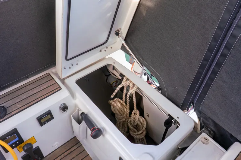 Slide: The Image of Open storage compartment on 2022 Beneteau Oceanis 461 sailboat, showing ropes and controls. - 56