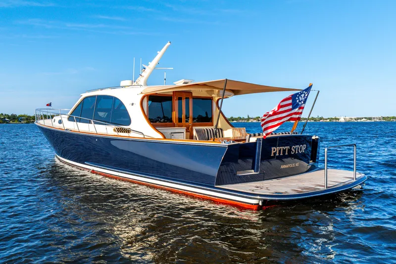 Slide: The Image of 2020 Palm Beach Motor Yachts PB55 on water, displaying American flag, sunny day. - 40
