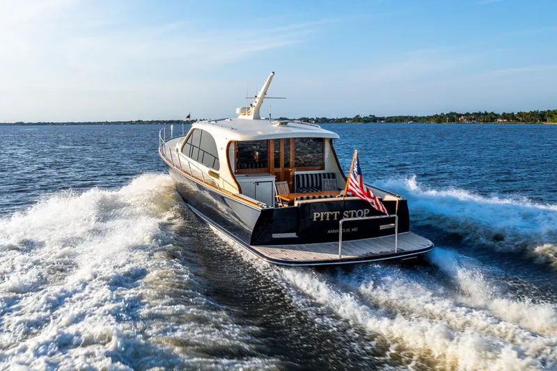 Slide: The Image of 2020 Palm Beach Motor Yachts PB55 cruising on open water, rear view with American flag. - 44