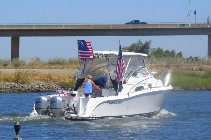 Slide: The Image of 2006 Pro-Line 32 Express boat cruising under a bridge, displaying American flags. - 5