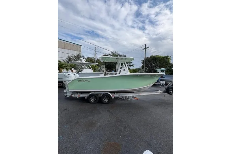 The Image of 2023 Sea Pro 259 DLX boat on trailer, parked outdoors under cloudy sky. - 0