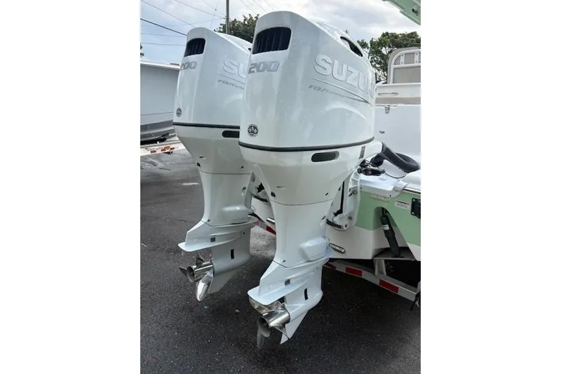 Slide: The Image of Twin Suzuki outboard engines on a 2023 Sea Pro 259 DLX boat, parked outdoors. - 15