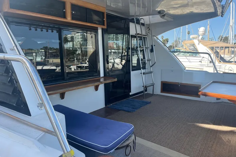 Slide: The Image of 1990 Mikelson 48 Sportfisher yacht deck with seating, ladder, and marina view. - 10