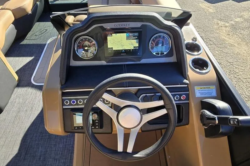 Slide: The Image of 2026 Godfrey Monaco 235 SFL boat dashboard with steering wheel and navigation display. - 14