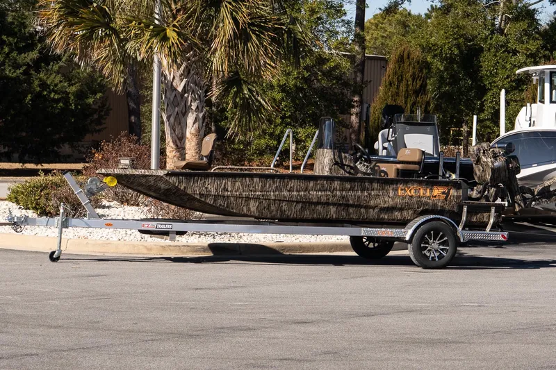 The Image of 2026 Excel 1860 Shallow Water F4 CC boat on trailer, parked outdoors. - 1