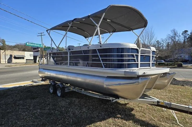 Slide: The Image of 2023 Godfrey Xperience 2286 SBX Sport Tube pontoon boat on trailer, parked outdoors. - 2