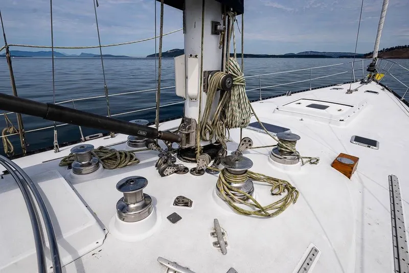 Slide: The Image of 1974 C&C 61 Ocean Racer/Cruiser deck with winches and ropes, sailing on calm waters. - 10